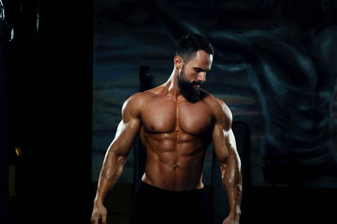 Leonardi, muskulor duke pozuar në palestër, duke përfaqësuar rezultatet e programeve të Transformohu për forcë dhe transformim fizik.