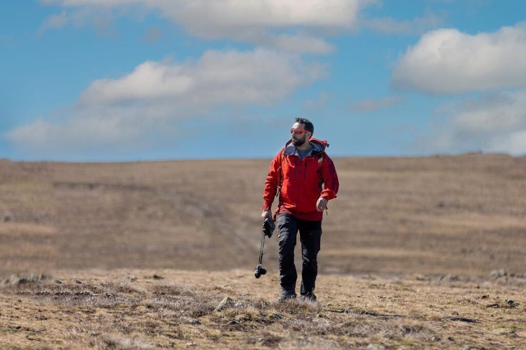 Një burrë duke eksploruar natyrën në një peizazh të hapur, duke simbolizuar frymën e aventurës dhe transformimit personal të promovuar nga Transformohu.